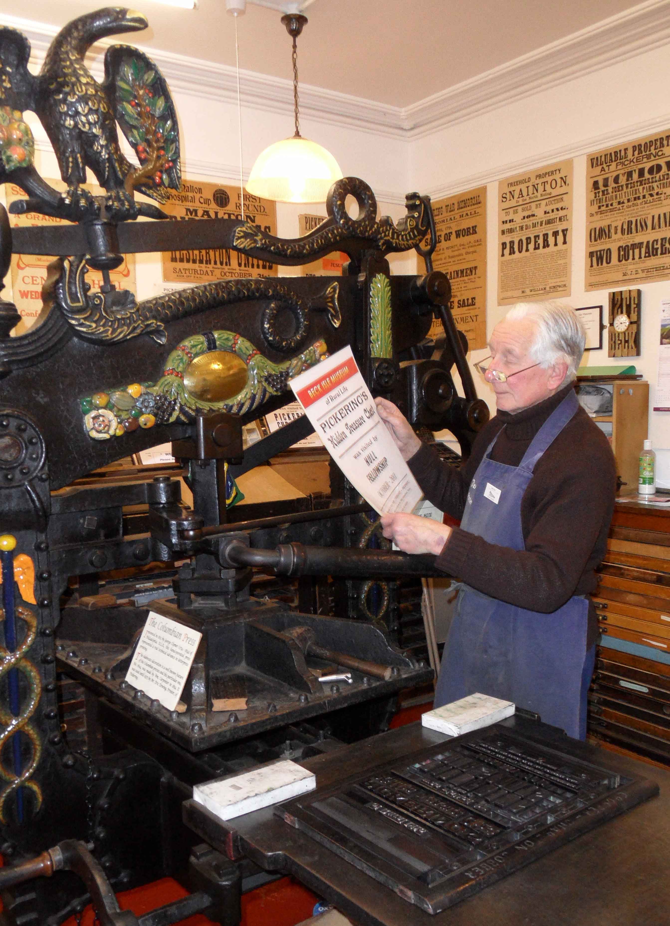 Volunteer printer holds up poster printed on museum's printing press